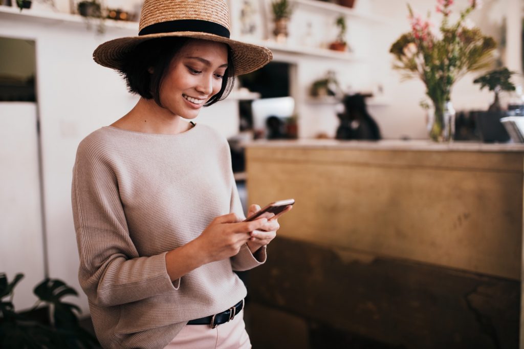 Woman smiling in a cafe with her mobile phone