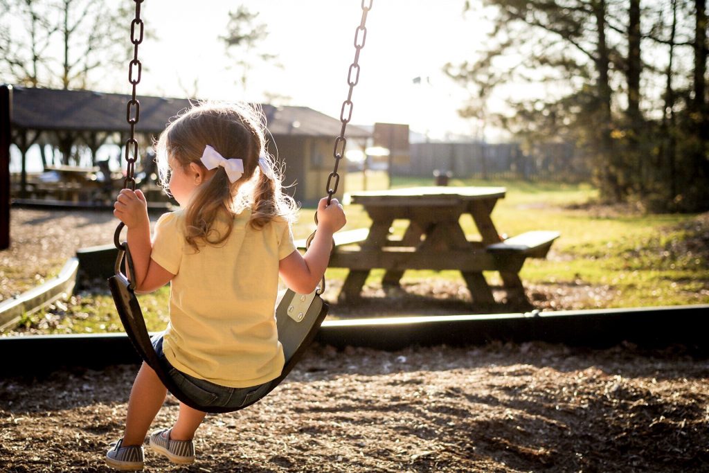 Little girl playing on a swing