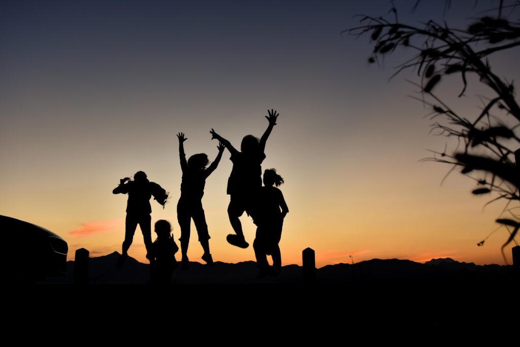 Happy children jumping outside in front of sunset
